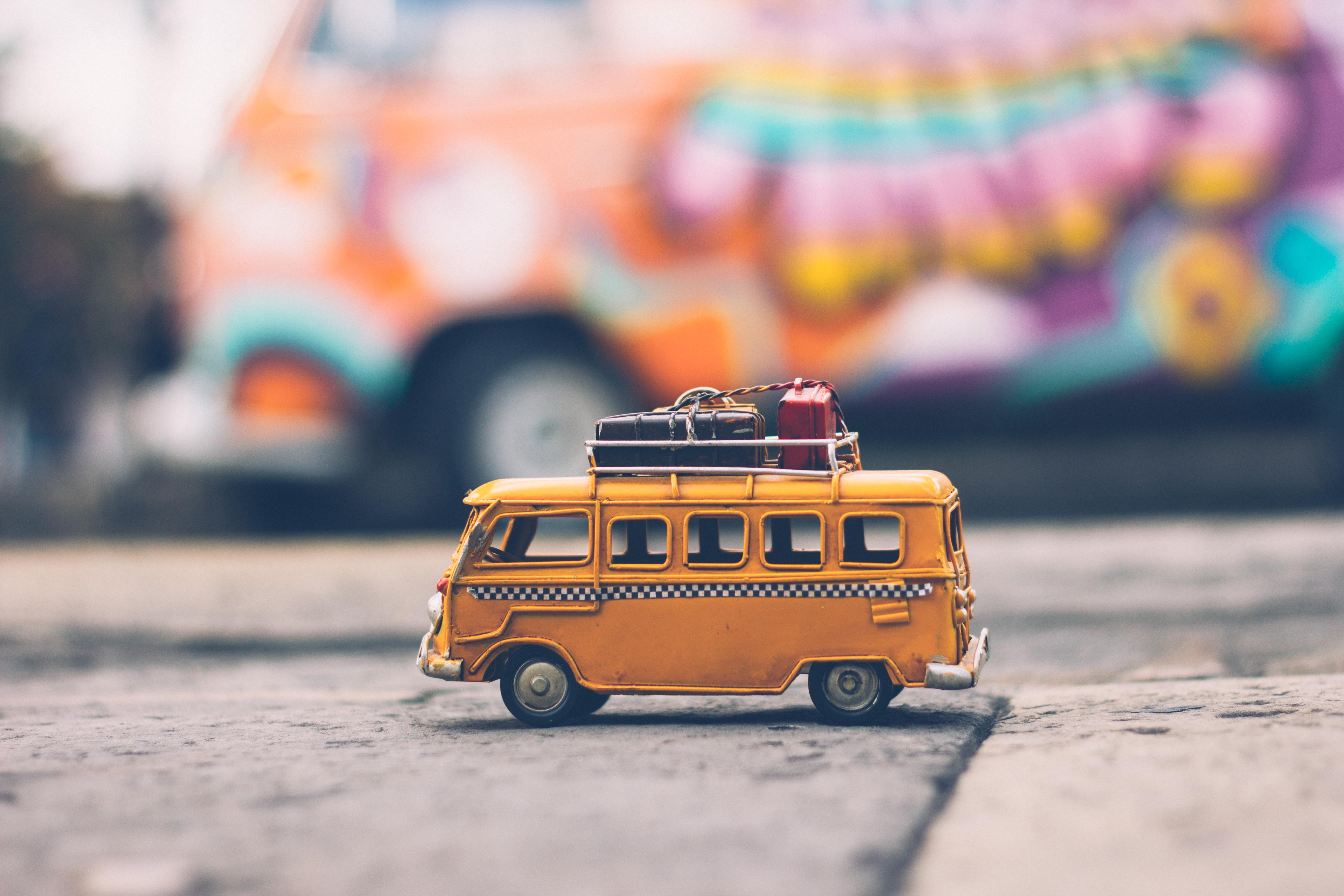 A yellow toy bus loaded with luggage on the roof